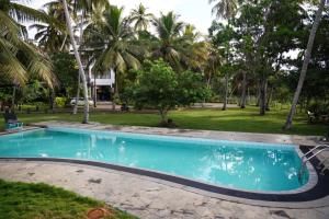 a swimming pool in a yard with palm trees at Lake Edge Resort in Hambantota