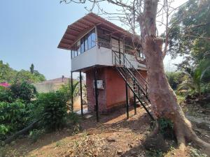 a small house on a hill next to a tree at TOMS' Cabin Farmhouse in Chauk