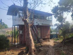 a house with a staircase next to a tree at TOMS' Cabin Farmhouse in Chauk