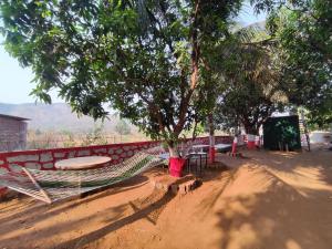 a hammock and a table and chairs under a tree at TOMS' Cabin Farmhouse in Chauk