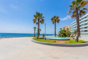 a park near the beach with palm trees and a building at Marina Luxury in Torrevieja