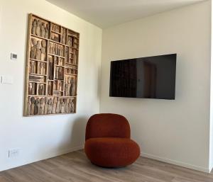 a room with a chair and a television on a wall at Tronc Verdi in Roeselare