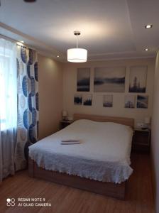 a bedroom with a white bed and a window at Кандавас 9 in Daugavpils