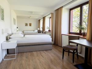 a bedroom with two beds and a table and a desk at Hotel Cvilín in Krnov