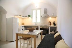 a kitchen with a table and a white refrigerator at Vasiliki guesthouse in Aroniadika