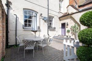 a patio with a table with chairs and an umbrella at Warwick Centre Townhouse Castle views in Warwick