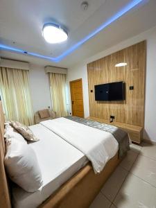a bedroom with a large bed and a flat screen tv at Supreme Apartments in Ibadan