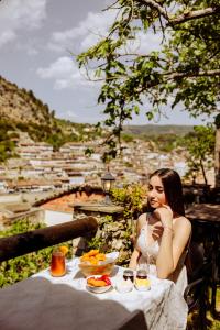a woman sitting at a table with food on it at Anhel Hotel in Berat