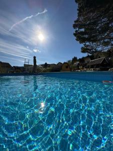 a large blue swimming pool with the sun in the background at Glamping Park in Mönichkirchen