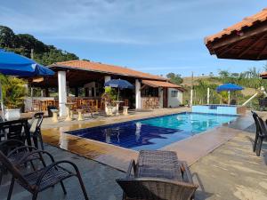 a large swimming pool with chairs and umbrellas at Pousada irmãos Oliveira in Lindóia +82 photos