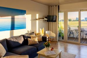 a living room with a blue couch and a balcony at Sonnenkoje in Fehmarn