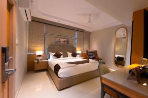 a bedroom with a large bed and a mirror at Dlite Rivera Premium Hotel Apartments in Bangalore