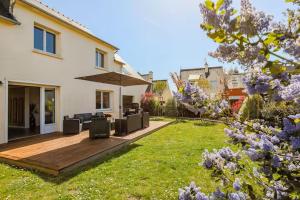 a backyard with a wooden deck with chairs and an umbrella at Grande maison familiale centre ville - 2km des plages in Beaussais sur Mer