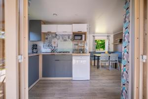 a kitchen with white appliances and a dining room at Camping Le Paradis Médoc in Saint-Laurent-de-Médoc