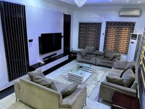 a living room with couches and a flat screen tv at Supreme Apartments in Ibadan