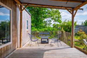 a porch with two chairs and a table on it at Camping Le Paradis Médoc in Saint-Laurent-de-Médoc