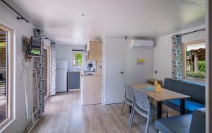 a caravan kitchen and dining room with a table and chairs at Camping Le Paradis Médoc in Saint-Laurent-de-Médoc