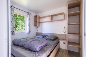 a bed in a room with a window and shelves at Camping Le Paradis Médoc in Saint-Laurent-de-Médoc