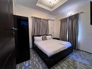 a bedroom with a bed in a room with curtains at Supreme Apartments in Ibadan