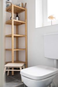 a bathroom with a white toilet and a shelf at Sonnenkoje in Fehmarn +63 photos