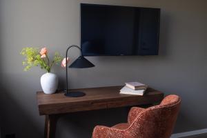 a desk with a television and a vase of flowers at Aspenäs Herrgård in Lerum