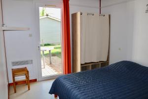 a bedroom with a bed and a sliding glass door at Chalet Au Petit Bonheur Piscine & Domaine calme in Rivières