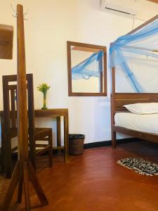 a bedroom with a bed and a table and a mirror at Baywings Rooms in Arugam Bay