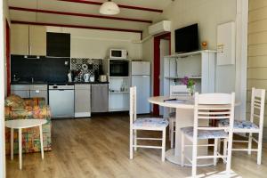 a kitchen with white appliances and a table and chairs at Chalet Au Petit Bonheur Piscine & Domaine calme in Rivières