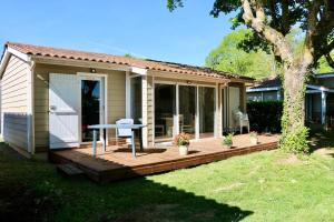 a house with a deck with a table on it at Chalet Au Petit Bonheur Piscine & Domaine calme in Rivières