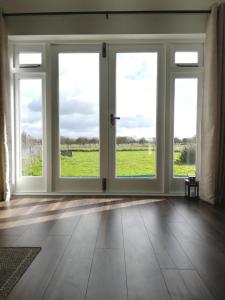 an empty room with large windows with a view of a field at Charming Countryside Chalet in Mégrit