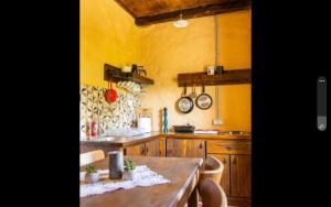 a kitchen with yellow walls and a wooden table at Old House Piperi in Podgorica +16 photos