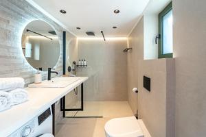 a bathroom with a sink and a toilet and a mirror at Twin Olive Villas in RhodesRhodes +34 photos
