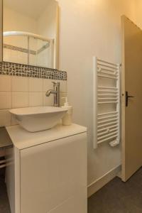 a white bathroom with a sink and a mirror at La Palette Fleurie in Laignes