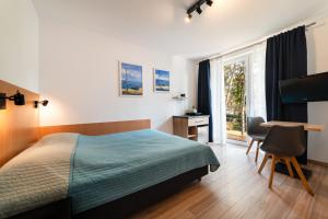 a bedroom with a bed and a desk and a window at Willa Juranda in Jurata
