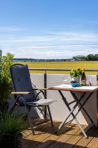 a chair and a table on a balcony with wine glasses at Sonnenkoje in Fehmarn