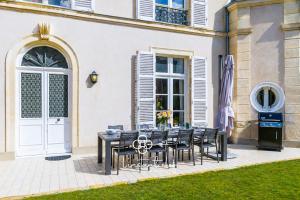 a table and chairs in front of a building at Villa élégante 5 chambres - 24H du Mans - Piscine Chauffée & Garage in Le Mans