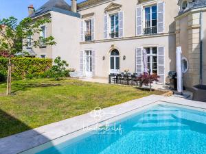a swimming pool in front of a house at Villa élégante 5 chambres - 24H du Mans - Piscine Chauffée & Garage in Le Mans