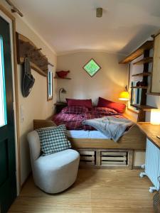 a bedroom with a bed and a chair at Zirkuswagen im Gutshof in Lutterberg