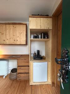 a kitchen with wooden cabinets and a small refrigerator at Zirkuswagen im Gutshof in Lutterberg