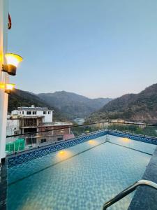 a swimming pool on top of a building with mountains at Hotel Hrishikesh High Tapovan in Rishīkesh