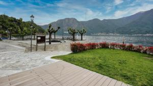 a park next to a body of water with mountains at Historic Borgo Lake Como Campidoglio 5 in Lenno