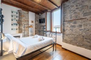 a bedroom with a bed and a stone wall at Historic Borgo Lake Como Campidoglio 5 in Lenno