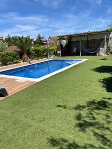 a swimming pool with green grass next to a house at Habitacion Monteazul in El Casar de Talamanca