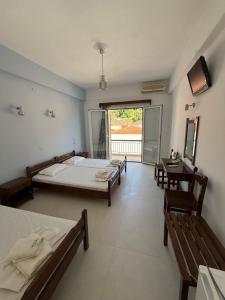 a bedroom with two beds and a window and two benches at Hotel Galini in Parga