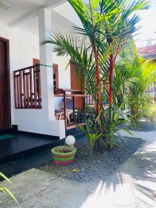a porch of a house with a table and some plants at Baywings Rooms in Arugam Bay