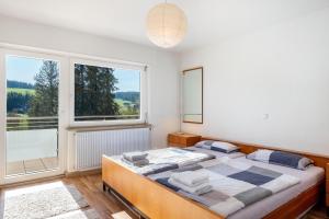 a bedroom with a bed and a large window at Haus Gutach in Schönwald