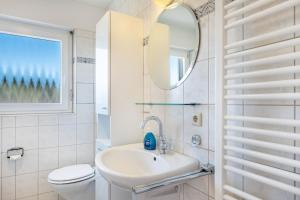 a white bathroom with a sink and a mirror at Haus Gutach in Schönwald +25 photos