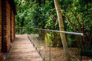 a wooden walkway with a fence and trees at Tawny Lodge in York +3 photos