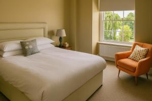 a bedroom with a bed and a chair and a window at The Lion Hotel in Builth Wells +4 photos