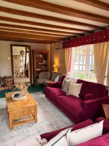 a living room with a red couch and a table at Mesopotamia Cottage in Clifton Hampden